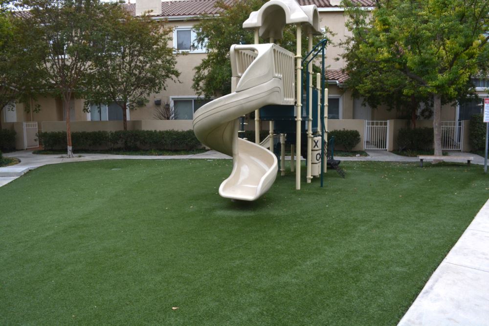 Playground area featuring professional artificial turf installation beneath play structures, providing a safe, durable, and low-maintenance surface for residential community recreation.