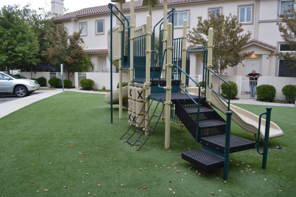 Playground with durable artificial turf installation providing a safe, low-maintenance surface for children at a residential community courtyard.